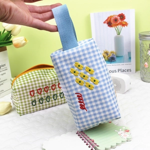 Detail of checkered canvas organizer bag featuring floral embroidery and sturdy handle