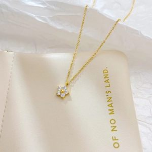 Elegant gold stainless steel flower pendant necklace with clear crystals on beige leather