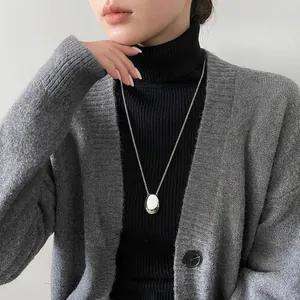 Polished silver oval pendant necklace detail on black knit sweater for women
