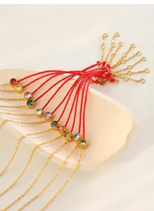 Detailed shot of red string bracelets with colorful zircons and gold-plated chains