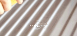 Detail of transparent thickened PVC gel being applied to a metal corrugated surface