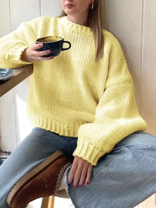 Close-up of yellow chunky knit texture on a loose-fit crewneck long sleeve sweater