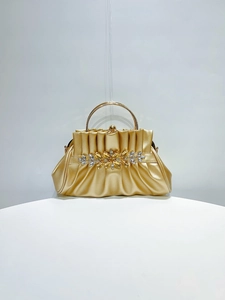 Macro shot of gold evening clutch featuring pleated fabric and rhinestone flower buckle