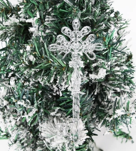 Close-up of vintage transparent key-shaped ornament hanging on a snowy Christmas tree