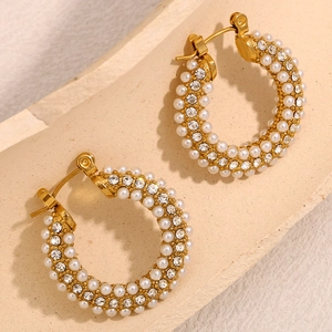 18K gold plated hoop earrings with pearls and cubic zirconia on a stone surface