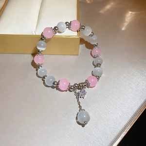 Close-up of pink and white cat eye bead bracelet with silver star pendant and crystals