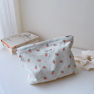 Detail of floral embroidery and white textured dots on cotton makeup bag with zipper