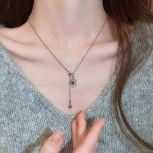 Gros plan du collier pendentif tournesol en œil de tigre porté avec des glands