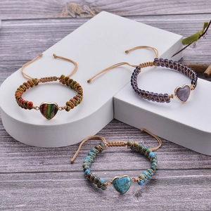 Detailed view of handmade woven heart bracelets with natural stones on a geometric display