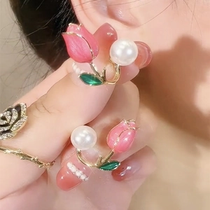 Close-up of pink tulip earrings with white pearl detail and matching gold rings for women