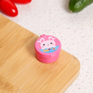 Close-up of pink mini sauce container with cartoon rabbit and Angel text on a wood board