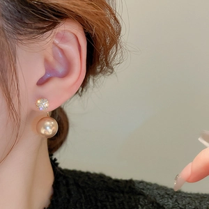 Close-up of elegant gold pearl drop earrings with sparkling rhinestones on model