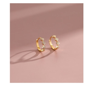 Macro detail of gold hoop earrings with sparkling square cubic zirconia on pink background