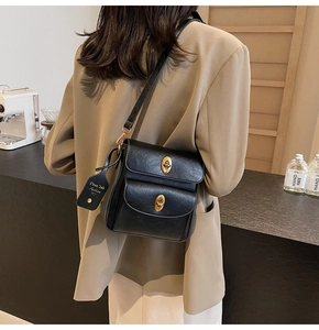 Detail of elegant black crossbody bag with vintage golden oval turn-lock closures