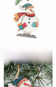Close-up of wooden snowman ornament with red scarf hanging on a festive pine branch