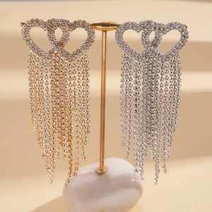 Detail of dangling heart earrings with crystal tassels on a gold jewelry display stand