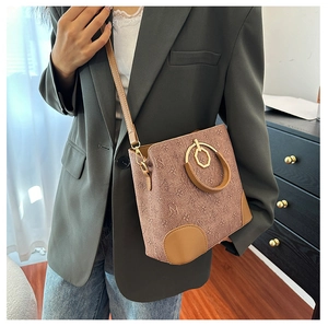 Fashionable monogram bucket bag with round metal handle shown on a model