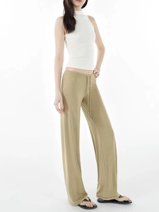 Side view of woman in white sleeveless top and khaki wide-leg drawstring casual trousers