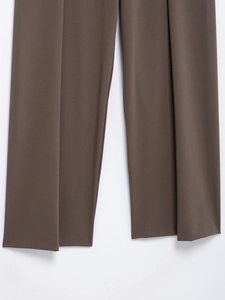 Detail of dark brown straight trousers with sharp pleats and smooth fabric texture