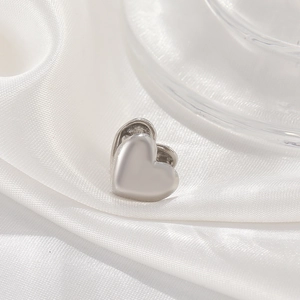 Minimalist 3D heart-shaped silver clip-on earrings on elegant white silk background