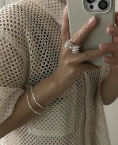 Detail of beaded bow ring and minimalist double-layer silver bracelets worn on wrist