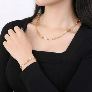 Golden necklace and bracelet set with interlocking oval links on a model's neck