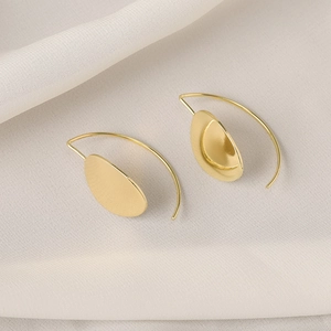 Minimalist gold oval disc earrings on white silk background with polished finish
