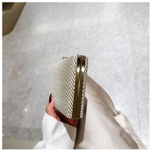 Detail of gold evening clutch bag with glitter texture and polished metal frame