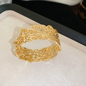 Detailed view of golden open cuff bracelet with intricate hollow butterfly pattern