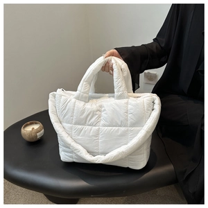 Detail of white quilted cloud tote bag showing puffy nylon texture and sturdy handles
