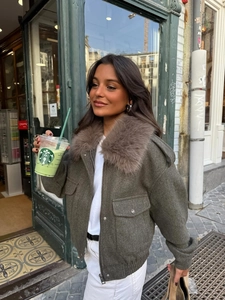 Detail of olive green bomber jacket with brown faux fur collar and utility pockets