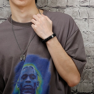 Detail of men's silver cross necklace and double-layer black stone beaded leather bracelet