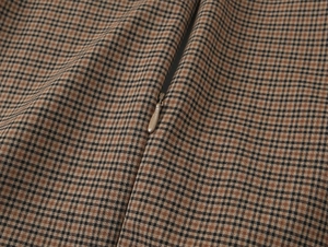Macro shot of invisible zipper and classic brown plaid fabric texture on the dress