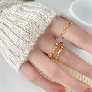 Minimalist wavy gold ring and double row beaded ring worn together for a layered style