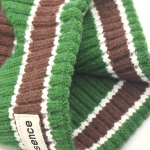 Close-up of green and brown striped ribbed knit beanie with a sewn sence fabric label