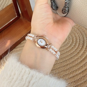 Elegant vintage oval watch with rose gold case and double-row pearl strap on a wrist