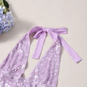 Dettaglio del top a lupetto con paillettes viola con lacci e trama di tessuto scintillante
