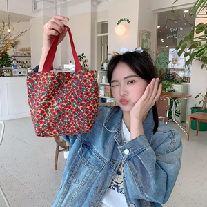 Detailed shot of retro floral corduroy handbag with red canvas handles for daily use