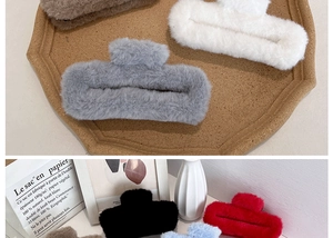 Detail of plush faux fur shark hair clips in various colors on a wooden tray