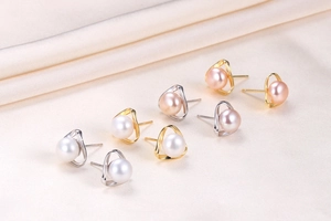 Macro detail of geometric pearl earrings in white, lavender, and pink on satin fabric