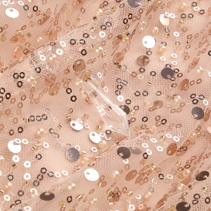 Macro detail of rose gold sequins and pearl embellishments on high-density mesh fabric