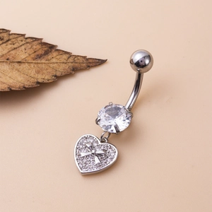 Vue macro d'un piercing de nombril argenté avec zircon et pendentif cœur étincelant