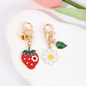 Detail showing enamel strawberry and daisy charms with heart lobster clasp on ceramic tray