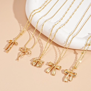 Détail d'un ensemble de 5 colliers dorés avec pendentif nœud et mailles variées