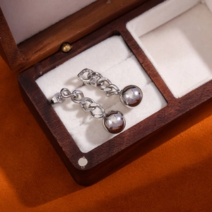 Detailed close-up of silver steel chain earrings with spherical drops on velvet