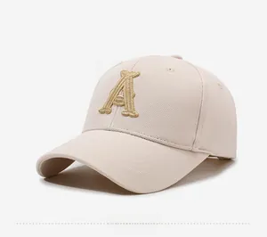Close-up of 3D gold letter A embroidery on a beige cotton baseball cap surface