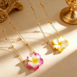 Detail van de bohemien gouden kralenketting met plumeria hangers voor vakantiestijl