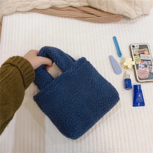 Vue de dessus d'un sac cabas en laine d'agneau bleu foncé avec accessoires du quotidien