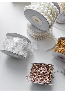 Detailed view of white snowflake bead chains and festive metallic star garlands in rolls
