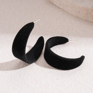 Macro shot of black flocked C-shaped earrings on stone base with silver needle detail